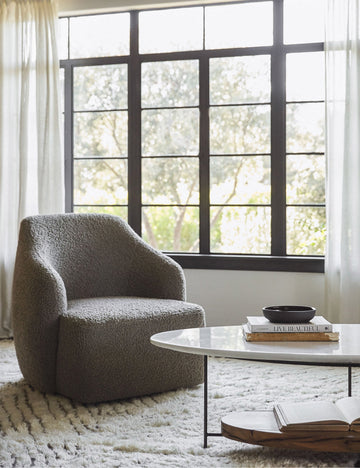 #showall::39840592068707 | The Tobi gray boucle swivel chair sits atop a plush ivory rug in front of a wall with large black-framed windows and sheet curtains