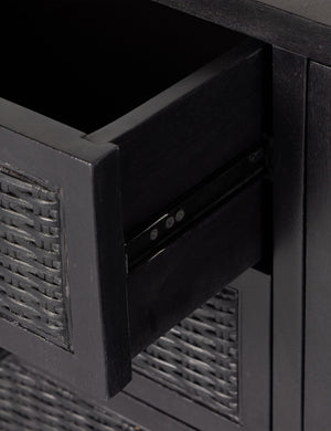 Drawer of the Isaura black cane-paneled media console.
