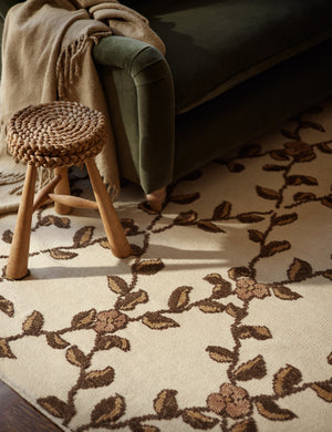 A close up of the Tillar Hand-Knotted Botanical Lattice Wool Rug by Jake Arnold under a couch and accent stool.