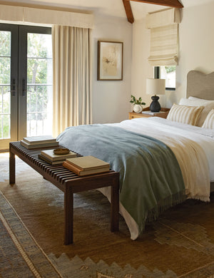 Olson mid-century slatted wood bench in walnut styled at the foot of a bed.