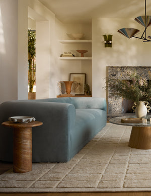 Mona round stone drink table styled next to a blue velvet sofa.