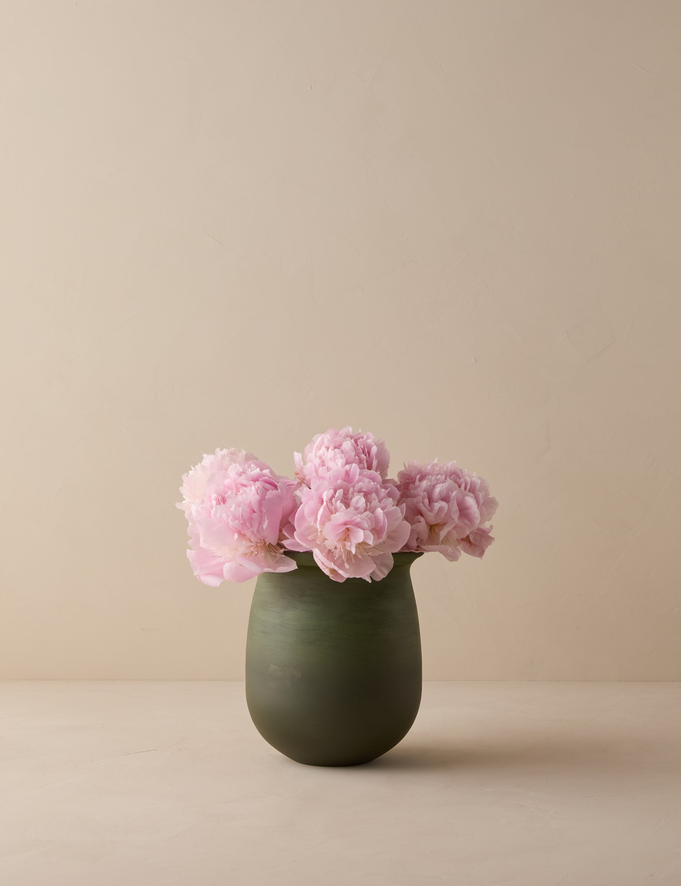 #color::olive | Campden matte green ceramic vase by Heidi Caillier filled with pink flowers.