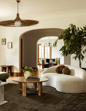 The Chiltern moss rug lays in a brown and ivory toned living room under a boucle sofa and a round wooden coffee table