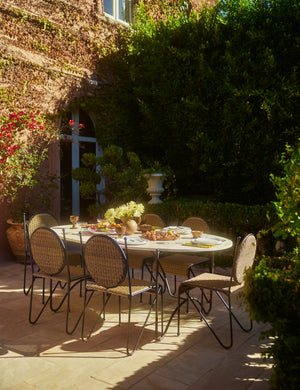 Six Ziggy modern wicker outdoor dining chair by Sarah Sherman Samuel placed around an oval outdoor dining table.