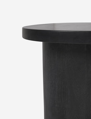 Close-up of the rim of the top of the Luna black wood round side table and the leg