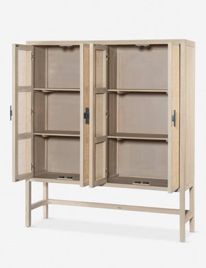 Angled view of the Hannah whitewashed mango wood cabinet with cane doors with all four doors open revealing its inner shelving