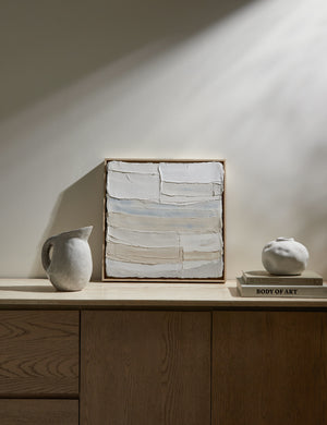 The Soft Views Framed wall art sits atop a wooden sideboard against an ivory wall next to a ceramic pitcher and vase