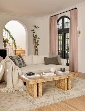  Natural Velvet Belmont Sofa sits in a living room behind a burl wood coffee table and atop a neutral-toned patterned rug