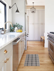 #size::1-9--x-2-10- #size::2--x-5- | The Rika black and white cotton machine washable mat with checkerboard pattern in its runner size lays in a kitchen with marble countertops 