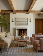 #showall::39867235795043 | Two Hayden double-armed black sconce lights hang on both sides of a landscape painting in a living room with warm-toned furniture