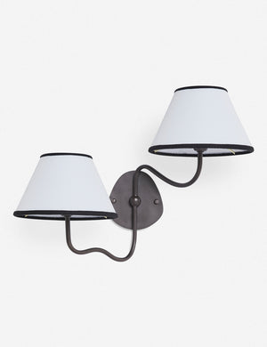 Magdalene black double sconce with a white linen shade that has a black trim, a round wall mount, and an arched arm