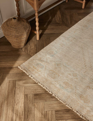 The lotus rug lays on a chevron wooden floor next to a jute basket and a sideboard with sculptural legs