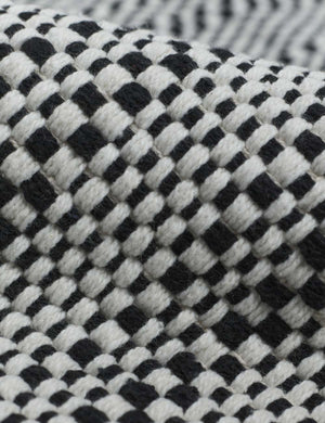 Close-up of the Saskia handwoven high contrast black-and-white patterned mat with thick fringe