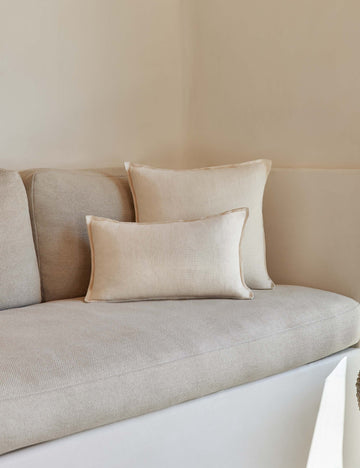 #color::light-natural #style::lumbar #fill type::with-feather-down-insert #fill type::pillow-cover-only | The arlo Light Natural flax linen pillow in its lumber and square sizes sit together on a natural linen sofa