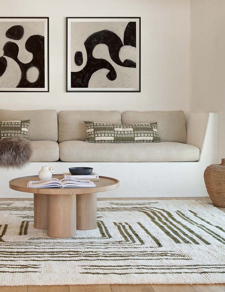 #size::14--x-40- | The Stonewalk green geometric throw pillow by Élan Byrd sits on a natural linen cushioned bench next to a round coffee table