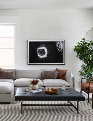 The Patrizia Leather Coffee Table sits in a living room with a gray sectional and a gray and white chevron rug