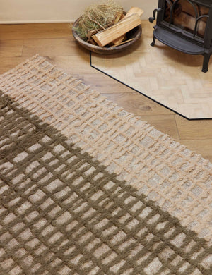 Close-up of the Terra handcrafted textured multicolored floor rug by Élan Byrd sitting in a room with a wood-burning fireplace atop hardwood floors